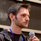 Photo of Mike Gerwitz holding a microphone in front of a blackboard